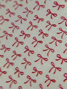 Macro view of 3D embossed red bow nail art stickers with elegant gold edges