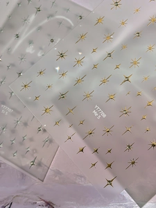 Macro detail of metallic gold and silver starburst nail stickers in YT7707 and YT7708 designs