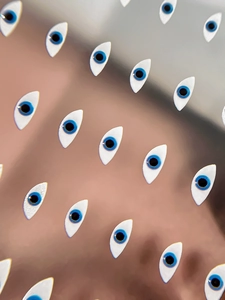 Macro detail of almond-shaped evil eye nail art stickers with blue and black patterns