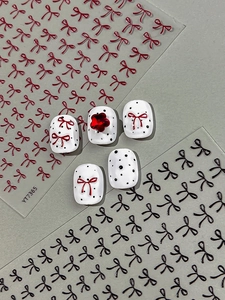 Detail of 3D bow nail stickers in red and black with white polka dot accent nails