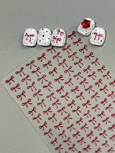 Close-up of 3D red ribbon bow nail stickers with vintage white polka dot nail tips