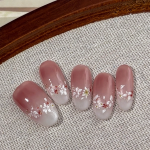 Pink and white gradient press-on nails with delicate floral patterns and glossy finish