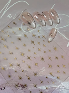 Detail of star-shaped nail stickers with gold metallic patterns on pink French manicure