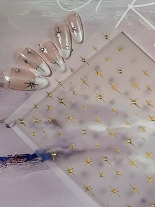 Macro detail of gold and silver starburst nail stickers on a white French manicure