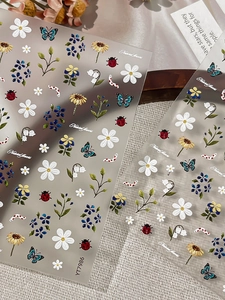Detail view of floral and insect 3D nail art stickers with daisies and butterflies