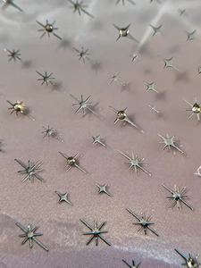 Macro shot of silver metallic star nail charms with sparkling reflective mirror finish