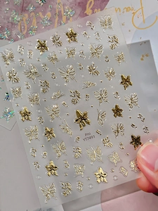 Macro shot of 3D champagne gold butterfly nail decals with metallic relief texture