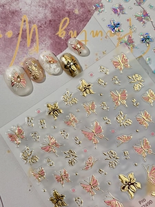 Detailed macro view of 3D embossed gold butterfly and rose floral nail art stickers