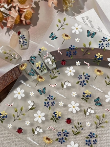 Detailed macro view of embossed nail stickers featuring white daisies and sunflowers