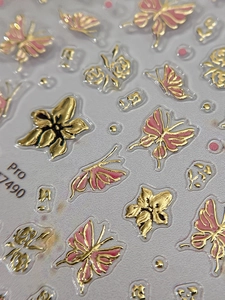 Macro shot of 3D embossed butterfly and flower nail stickers with gold metallic outlines