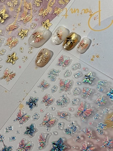 Macro view of gold embossed and iridescent butterfly nail art stickers with 3D floral details