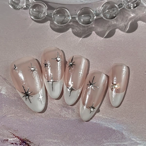 Nude pink French star stiletto nails with silver metal crosses and sparkling rhinestones