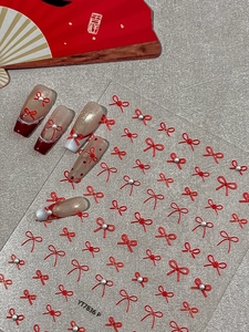 Detailed view of red bow nail stickers with pearls and 3D textured Chinese style design