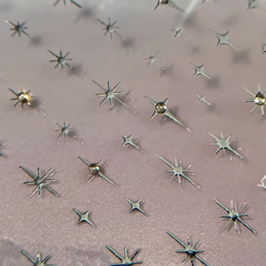Micro shot of shiny silver star nail art stickers in various shapes on a soft background