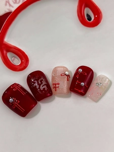 Macro shot of New Year nail stickers featuring red Chinese knots and pearl accents