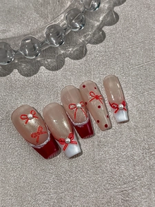 Detailed macro view of long trapezoid pink press-on nails with 3D red bows and pearls
