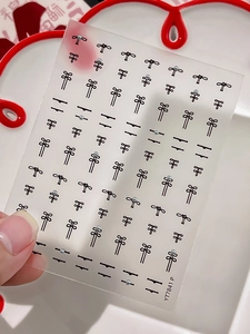 Macro view of Chinese style bow nail stickers with pearls and black line art patterns