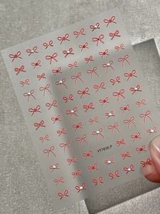 Close-up of red bow nail art stickers with silver bead accents on sheet YT7836 P