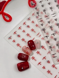 Detail of vintage Chinese style bow nail art stickers with silver pearls on red nails