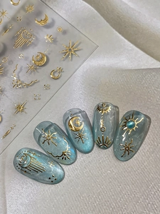 Detail of 3D metallic gold moon and star nail stickers on blue cat-eye textured nails