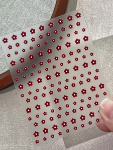 Close-up of 5-petal red plum blossom embossed nail stickers with white dot accents