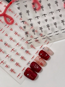 Macro detail of 3D Chinese knot nail stickers with pearls on wine red and plaid nails
