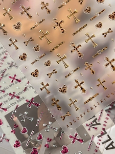 Close-up of 3D metallic gold nail stickers featuring leopard print crosses and hearts