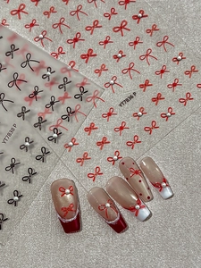Detail of 3D bow nail stickers with pearls on French tips and long red coffin nails