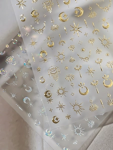 Detail view of 3D celestial nail stickers with gold foil and holographic laser effects