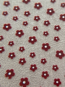 Macro detail of red embossed five-petal flower nail art stickers with silver center accents