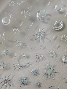 Macro shot of 3D holographic silver celestial nail stickers with moon and star patterns