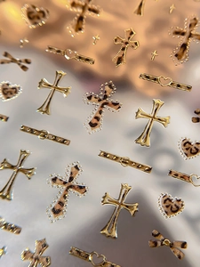 Close-up of leopard print heart and cross nail art stickers with metallic gold finish