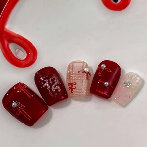 Festive red press-on nails with 3D bow knots, pearls and silver glitter accents