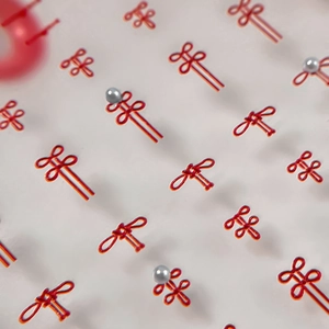 Traditional red Chinese knot nail charms with white pearls in an elegant array pattern