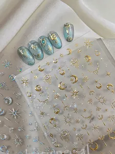 Close-up of gold and laser silver celestial moon and star nail art stickers on blue nails