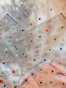 Macro shot of 3D gold embossed star and sunburst nail art stickers on clear film