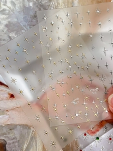 Macro detail of metallic gold and silver star nail stickers with cross star designs