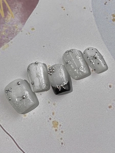 Macro view of square press-on nails featuring 3D silver bows and glitter details