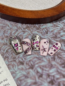 Macro shot of handmade press-on nails with silver chrome finish and pink leopard patterns