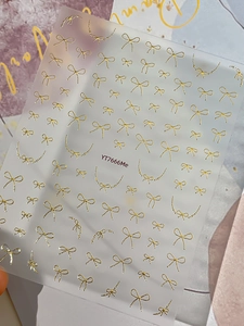 Macro shot of gold metallic bow and chain nail art stickers on matte backing sheet