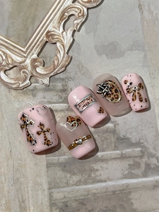 Detail of pink leopard print nail art stickers with metallic cross and star charms