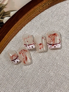 Detail of milky white press-on nails with red bows, polka dots and French tip design