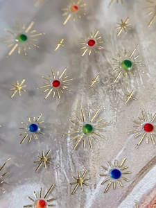 Macro shot of 3D star nail stickers with colorful gemstones on a textured surface