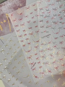 Detailed close-up of bow knot nail stickers in gold and silver glitter designs