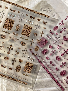 Close-up of leopard print nail stickers with cross and heart patterns in warm tones