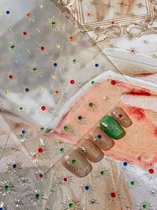 Detailed view of gold star nail stickers with colorful crystal accents on fingers