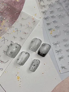Macro detail of silver bow nail stickers with 3D embossed texture and pearl accents