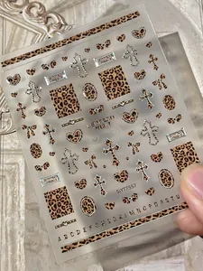 Detail view of leopard print nail decals with silver metallic heart and cross designs