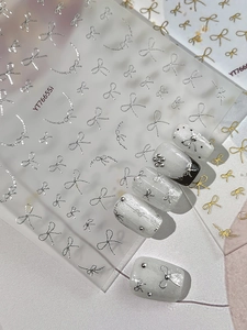 Detailed view of 3D metallic ribbon bow nail art stickers in gold and silver finishes