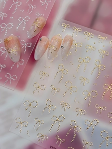 Detail of 3D metallic bow nail stickers in gold and silver on gradient nails